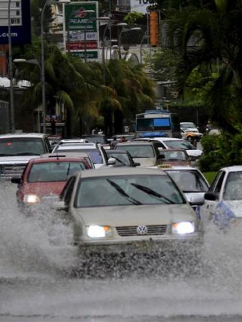 Vehicles drive through a street flooded by heavy rains caused by tropical storm Carlos, in...