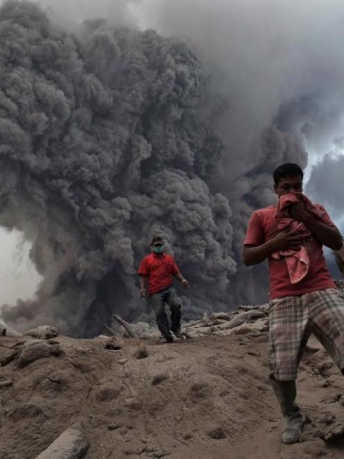 Villagers run on ash during the eruption of Mount Sinabung. REUTERS/Stringer