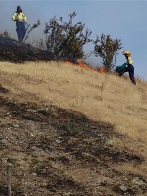 Volunteer firefighters survey  the scene of a grass fire near Tarras yesterday afternoon. Photo...