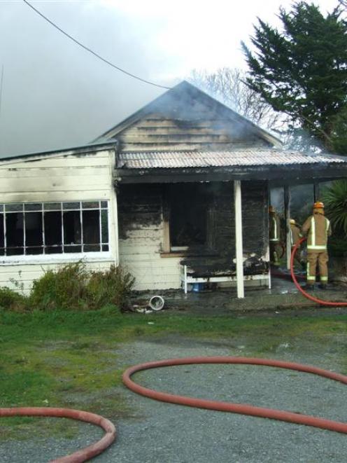 Volunteer firefighters try to save this Kaitangata home yesterday  morning. Police and the Fire...