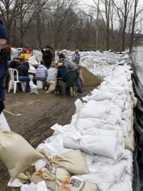Volunteers create a wall of sandbags to protect homes from flooding after several days of heavy...