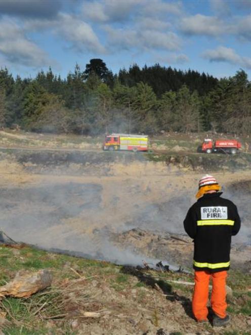 Waitaki rural firefighters dampen hot spots following a large fire near Palmerston on Saturday....