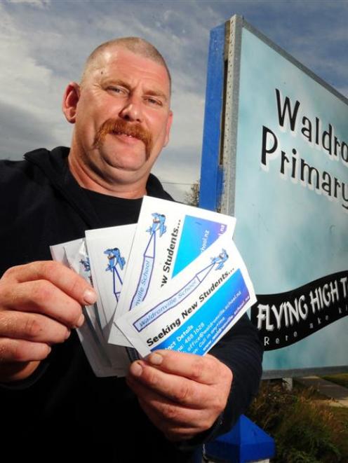 Waldronville School board of trustees chairman Keith Brandish holds fliers aimed at attracting...