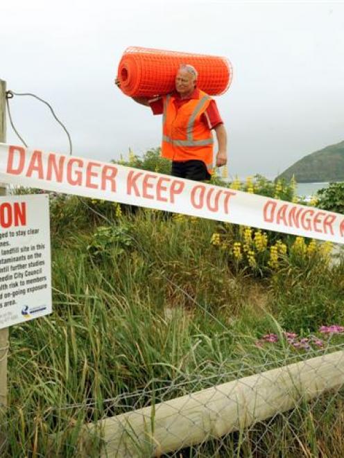 Warning signs and danger tape are installed by Delta worker Gray Townsend at Middle beach, near...