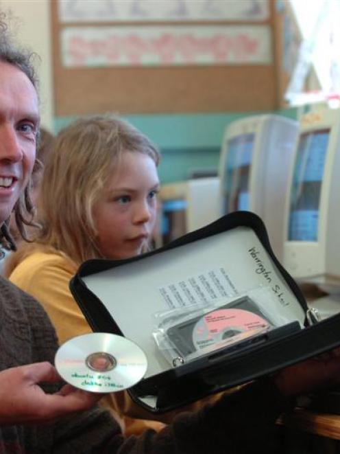 Warrington School principal Nathan Parker and Florence Sorrel (9) compare a single software disk,...