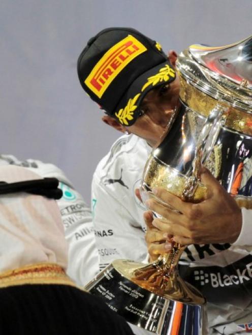 Watched by teammate Nico Rosberg, Lewis Hamilton kisses the trophy after winning the Bahrain F1...