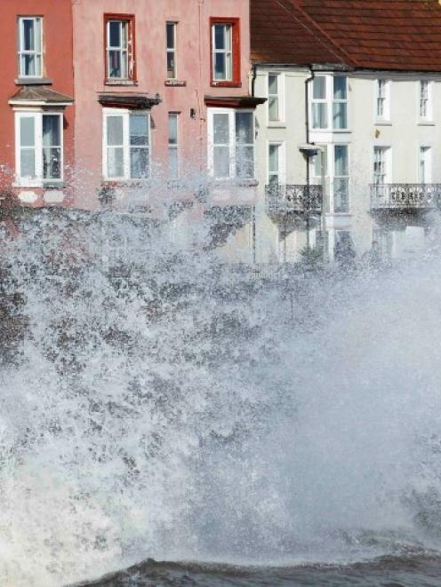 Waves crash against an already damaged railway line and buildings at Dawlish during storms in...