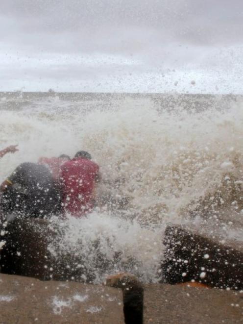 Waves crash into people sitting by the shore of the Bay of Bengal before cyclone Mahasen...