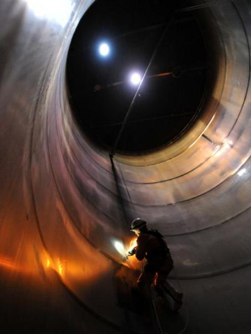Welder Murray Ewing uses a grinder inside a milk silo at Fonterra's Edendale plant yesterday....