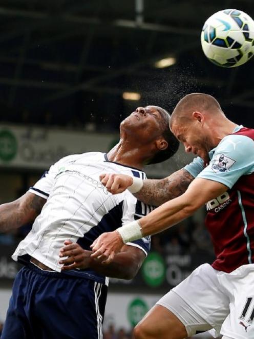 West Bromwich Albion's Andre Wisdom (L) heads clear from Burnley's Michael Kightly during their...