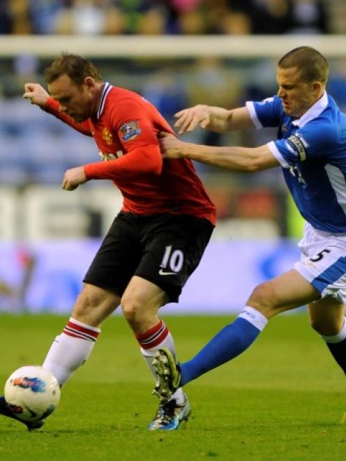 Wigan Athletic's Gary Caldwell (R) challenges Manchester United's Wayne Rooney during their...