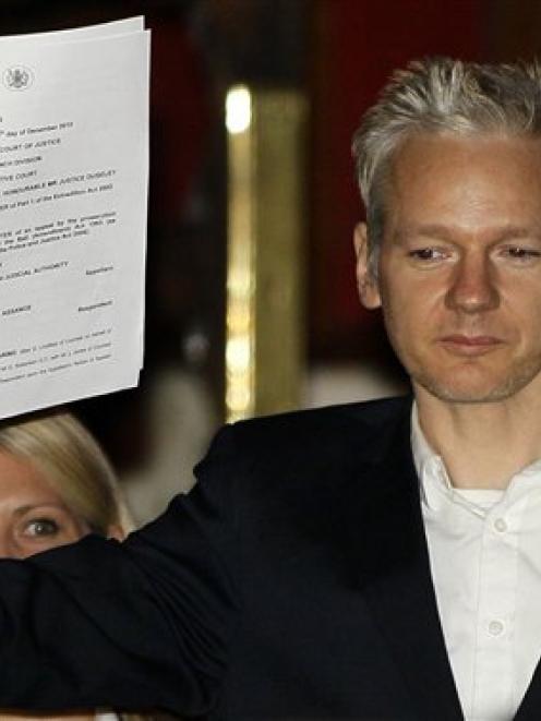 WikiLeaks founder Julian Assange holds up a court document for the media after he was released on...