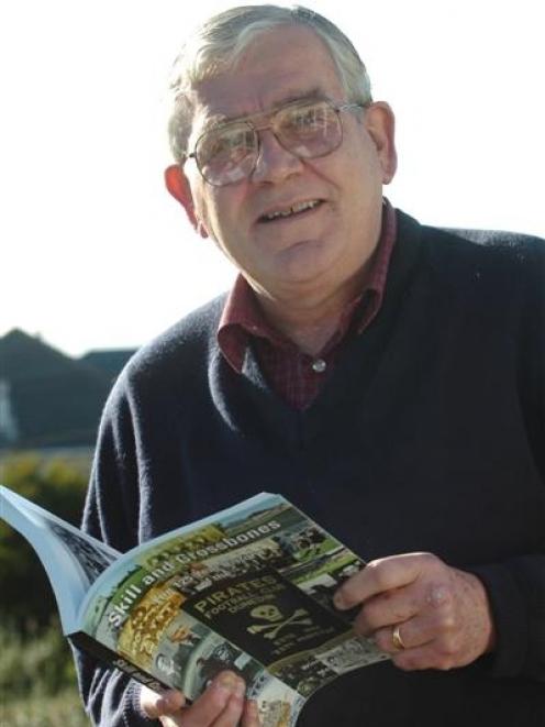 Winston Cooper holds a copy of his book 'Skill and Crossbones: The 125-Year History of the...