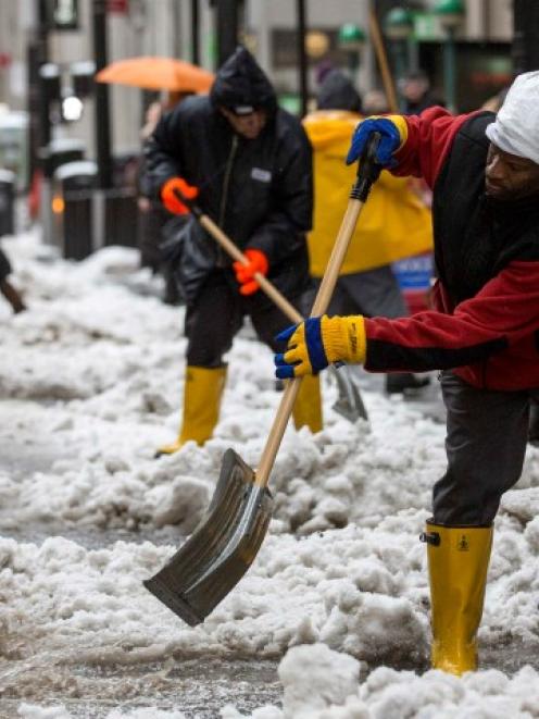 Workers clear snow in New York's financial district near Wall St. REUTERS/Brendan McDermid