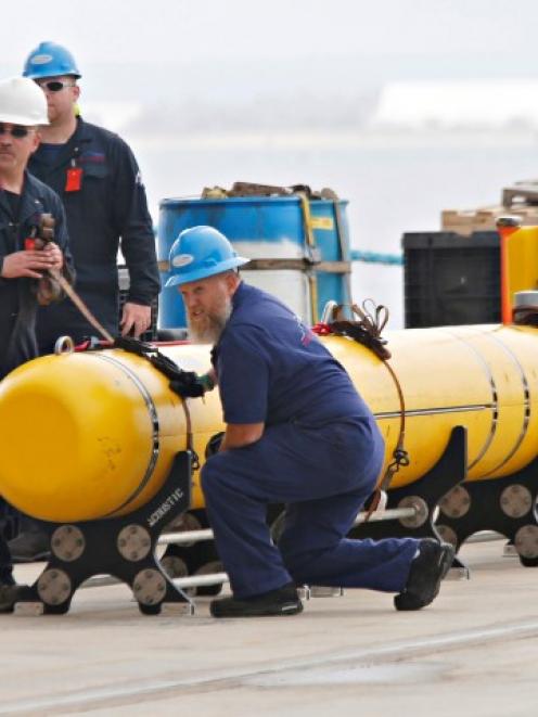 Workers help secure a Phoenix underwater mapping robot before it is loaded on to the Ocean Shield...