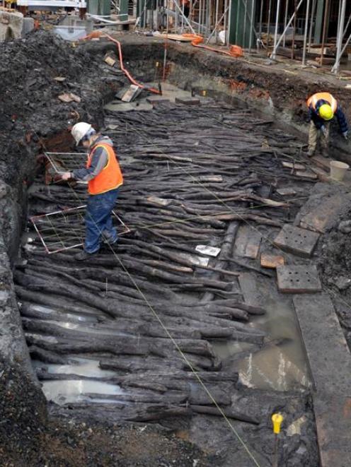 Workers in Dunedin examine the historic manuka causeway unearthed at the Wall Street mall...