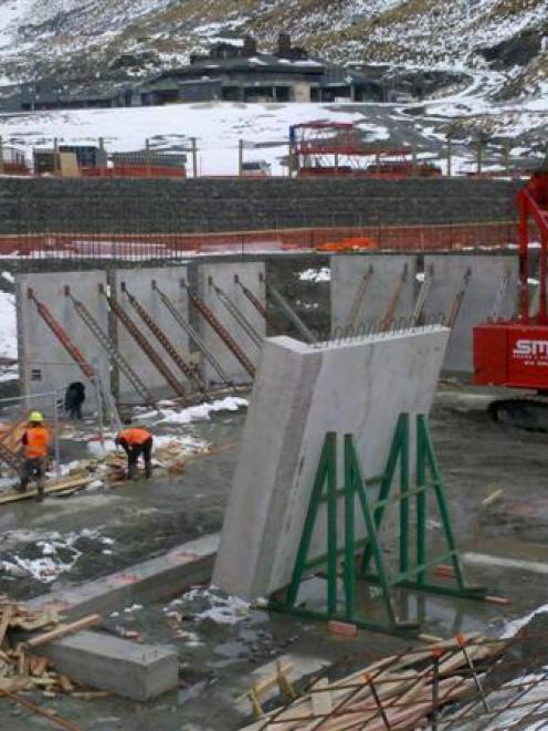 Workers last week erect the concrete wall panels of the $20 million base building under...