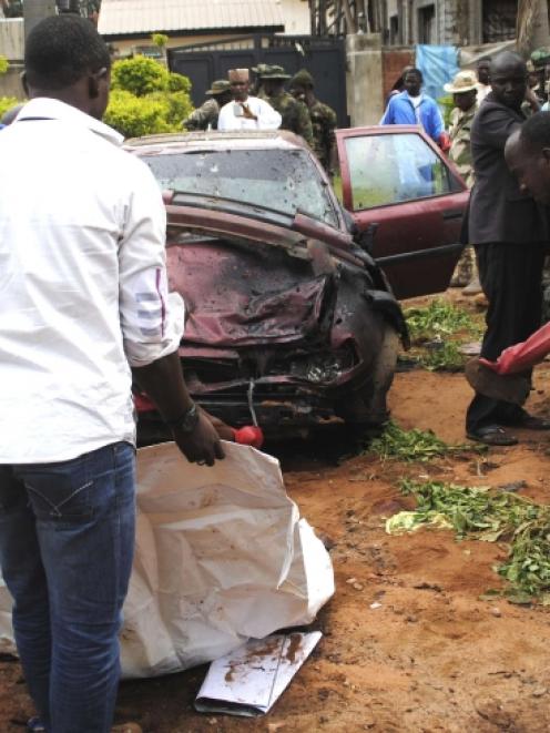 Workers pick up items at the scene of a bombing in Kaduna. Photo by Reuters