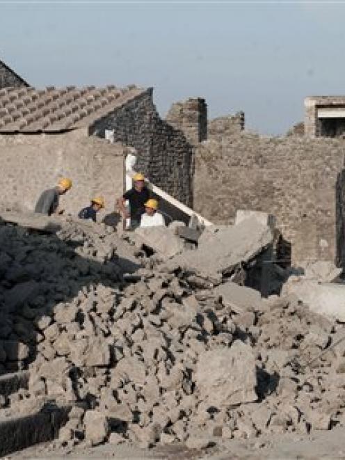 Workers stand among debris in the ancient Roman city of Pompeii. (AP Photo/Salvatore Laporta)