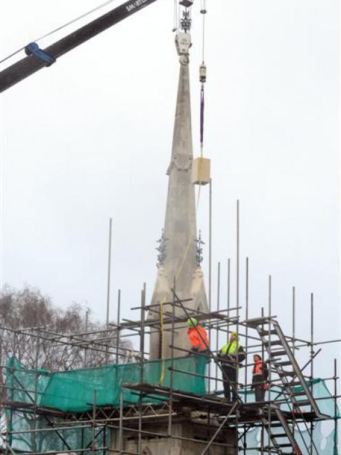 Workmen watch as one of four replacement stone finials is lifted into place on the Larnach tomb....