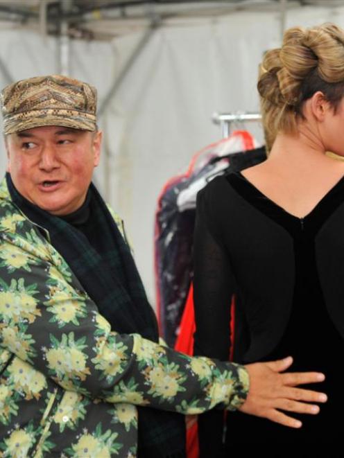 World co-founder Francis Hooper fits one of his gowns to a model backstage at the iD Dunedin...