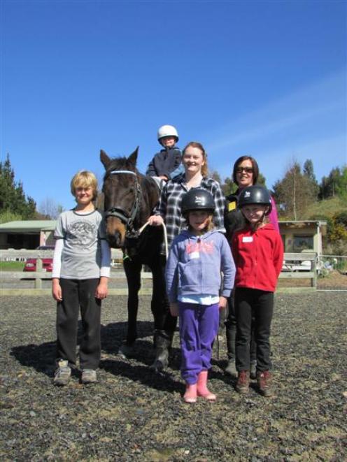 Young disabled rider Tyler Harvey (7), atop horse Billy, is ready to set off for a ride. Joining...
