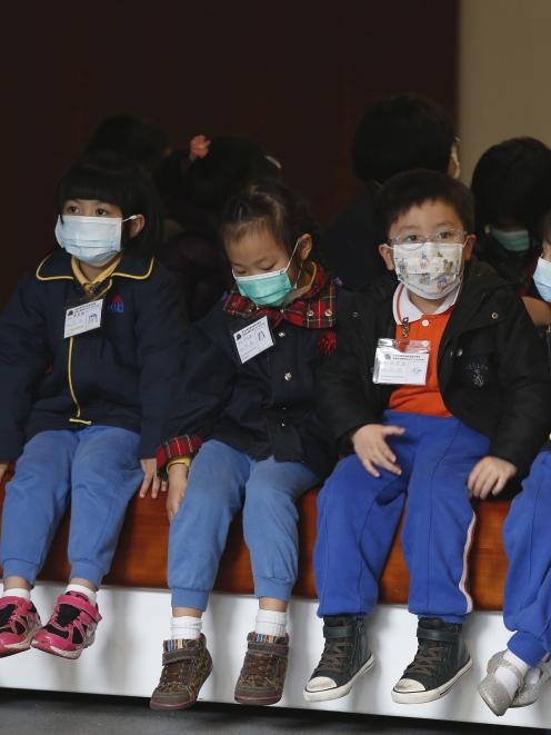 Young students, wearing masks to prevent flu, visit the Legislative Council on a school trip in...