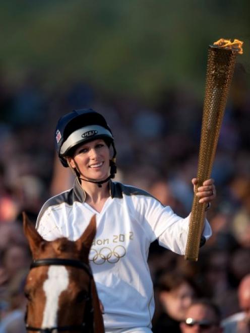 Zara Phillips holds the Olympic torch while riding through Cheltenham race course in Cheltenham...