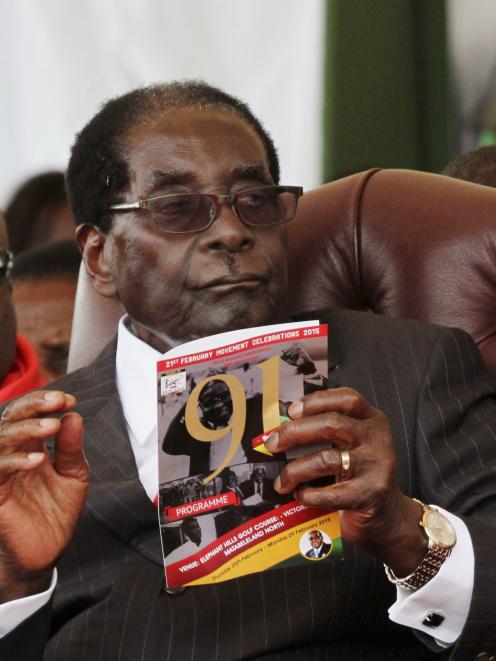 Zimbabwe President Robert Mugabe holds a booklet during his 91st birthday celebration in Victoria...