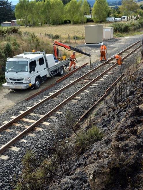 KiwiRail staff work beside scrub that was on fire near Gladstone Rd North, Mosgiel, yesterday....