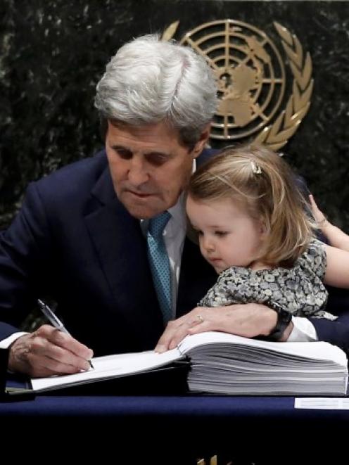 US Secretary of State John Kerry holds his granddaughter Isabelle Dobbs-Higginson as he signs the...