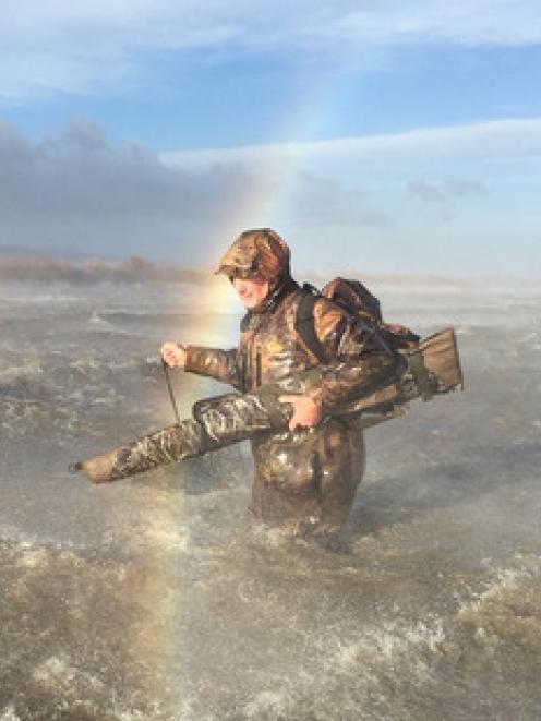 Duckshooter Andy Tannock struggles through waves as he abandons his maimai on Lake Wairarapa...
