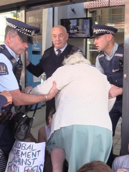 Police help Margaret Saunders into the bank on Thursday. Photo by Craig Baxter.