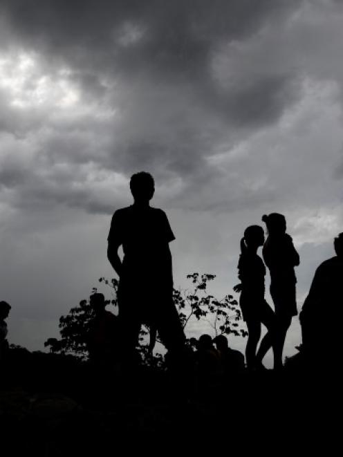 People are silhouetted at the landslide site. REUTERS/Jorge Cabrera