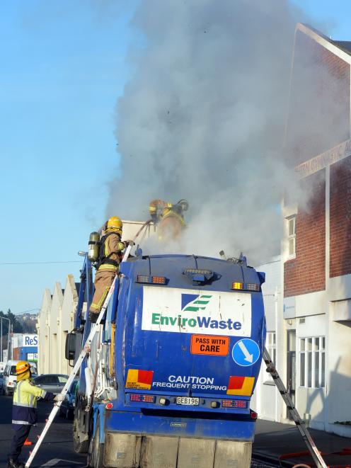 Firefighters dampen down smouldering rubbish on board  a waste disposal truck in Vogel St...