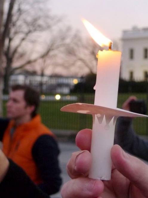 Supporters of gun control legislation hold candles during a rally in front of the White House in...