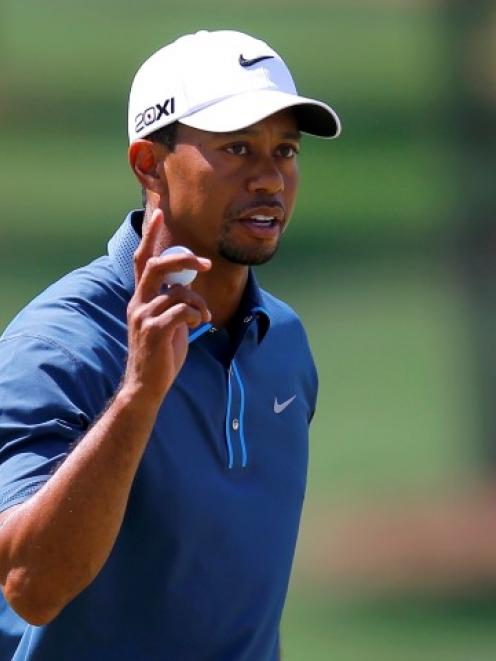 Tiger Woods holds up his ball after sinking a birdie putt on the seventh green during third round...