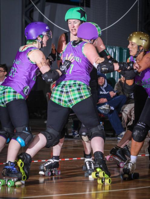 Charmaine Reveley, aka Little Yellow Jacket, (centre) gets a push in the back during a roller derby match. Photo supplied.