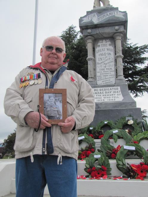 Alistair Moore, of Millers Flat, holds a photo of his late father, returned serviceman Bill Moore, during the Alexandra Anzac service yesterday. Mr Moore sen served in World War 2 in Egypt, Italy and Crete. Photo: Pam Jones.