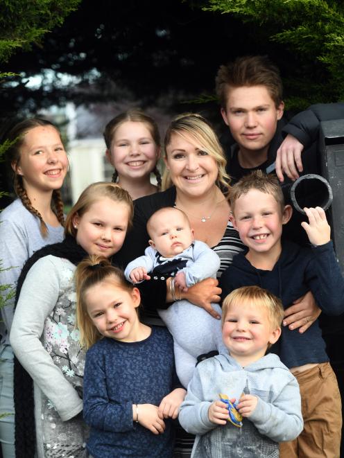 Olivia Bungard holds 9-week-old Emmett while surrounded by the rest of her brood. Clockwise from...