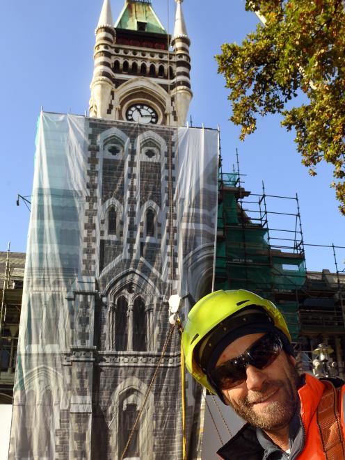 Adgraphix sales consultant Jono Gallacher in front of the clocktower after it was covered by a sheet of printed scrim for the benefit of graduates. Photo: Stephen Jaquiery.