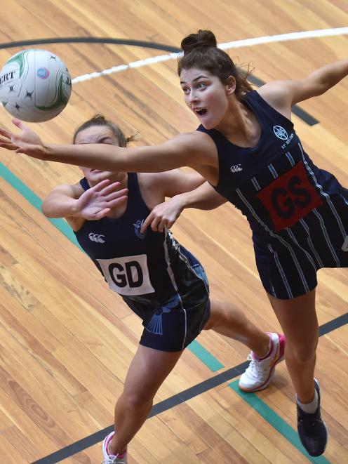 St Hilda’s shooter Georgia Heffernan (right) leaps above Columba College goal defence Ryelee...