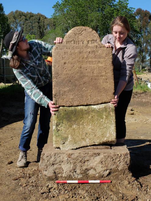 Archaeology students Teina Tutaki (left) and Alana Kelly hold up Henry Pim's headstone after it was found broken and buried at the St John's burial ground at Tokoiti. Photo: Supplied