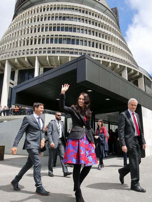 Prime Minister Jacinda Ardern, walking with partner Clarke Gayford, acknowledges the crowd outside parliament, in Wellington, yesterday. Photo: Getty Images