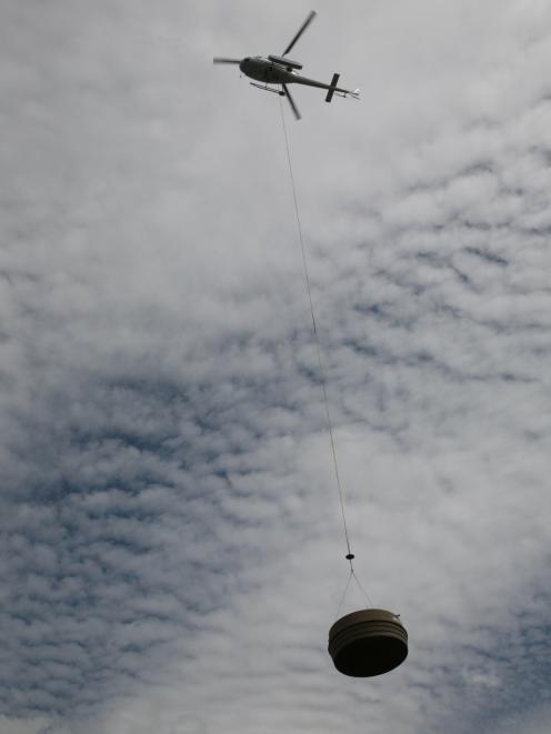 A Wanaka Helicopter lifts the second of two disused water tanks from Ruby Island and transports it to the mainland last Friday. Photo: Kerrie Waterworth