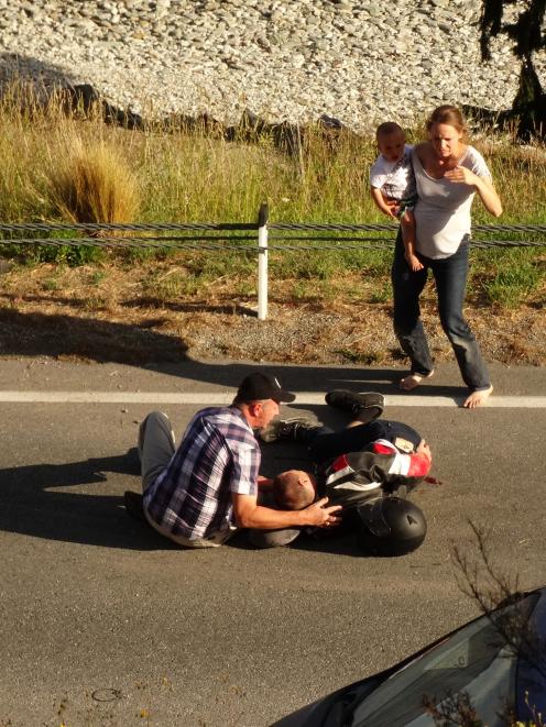 Members of the public help an injured motorcyclist in Fernhill Rd, Queenstown, last night. Photo: Paul Taylor