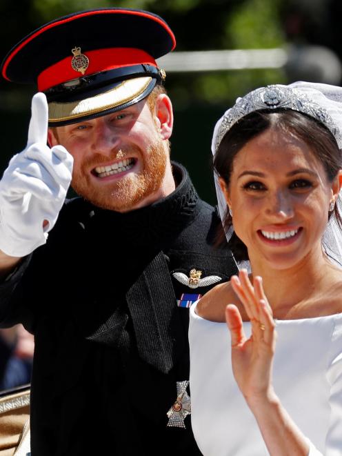 The Duke and Duchess of Sussex wave as they ride in a horse-drawn carriage after their wedding...