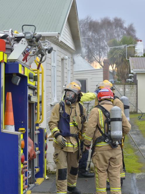 Firefighters start to pack up after extinguishing a house fire in Rutherford St yesterday morning. Photo: Gerard O'Brien