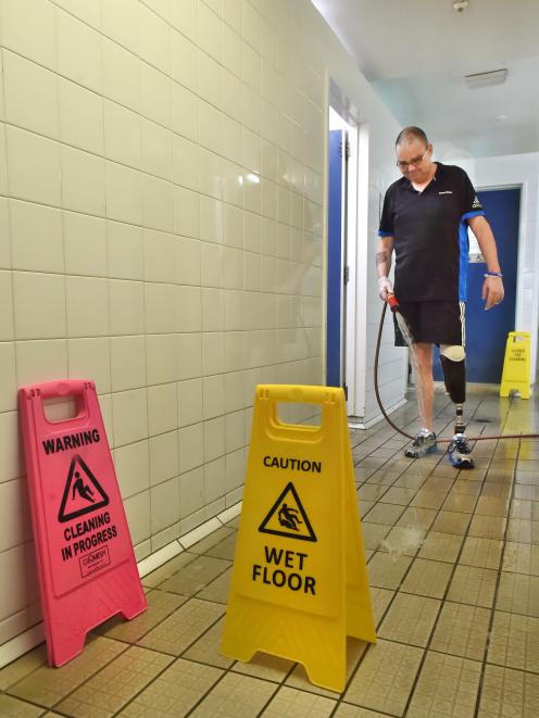 Dunedin City Council aquatic services worker Alan Davidson cleans defective tiles in the family...