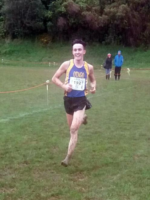 Oli Chignell smiles as he nears the finish line to win the men’s national cross-country title in...